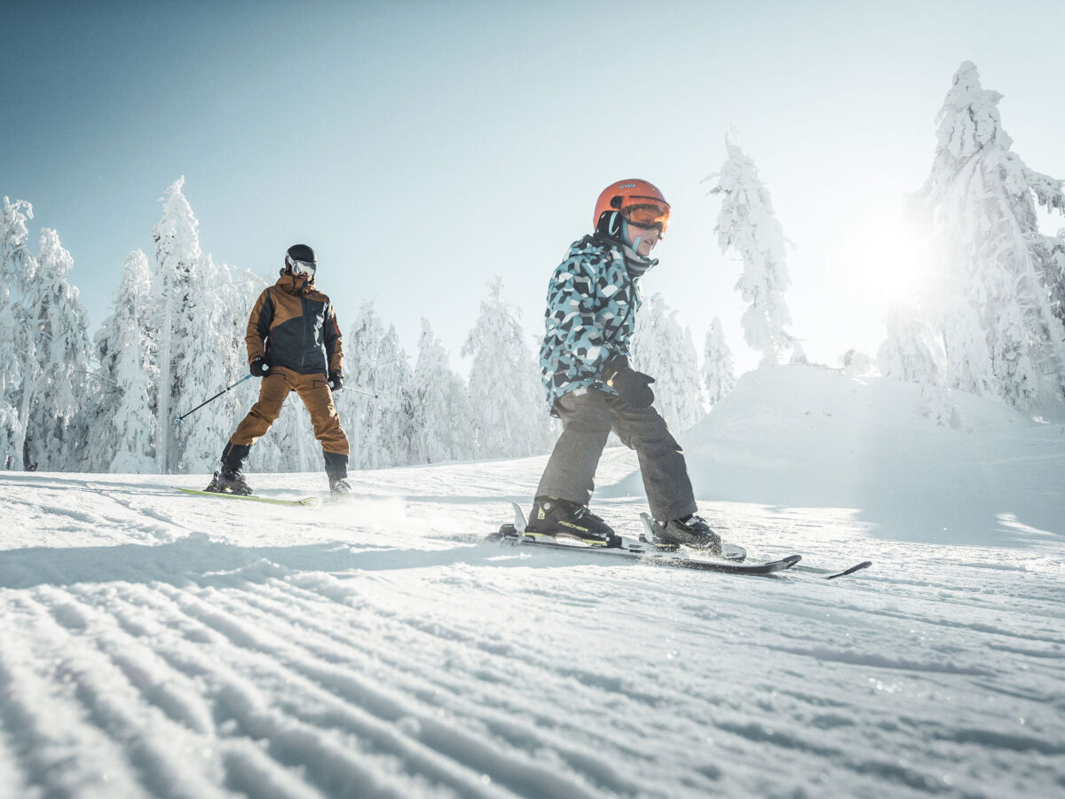Mann mit Kind beim Skifahren.